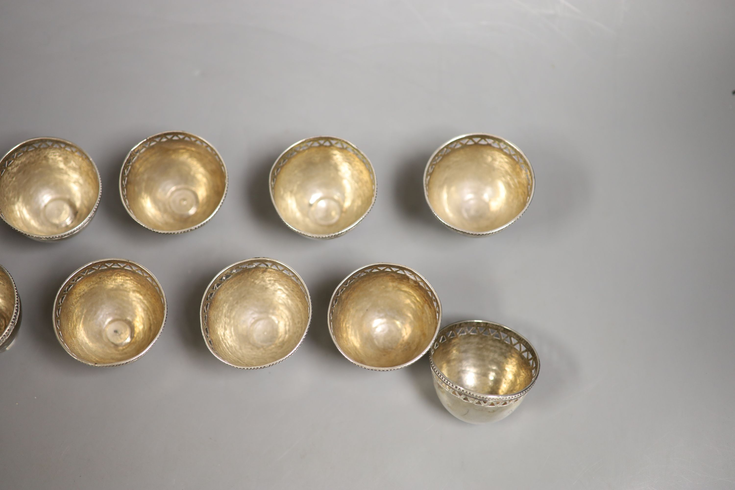 A set of twelve pierced small white metal footed cups